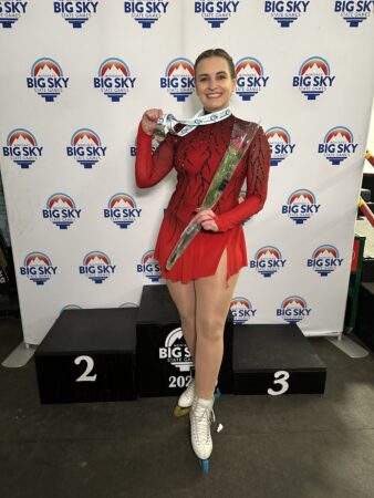 Student Doctor Kasey Smith smiles on the podium of the Big Sky Figure Skating Games, holding her medal. 